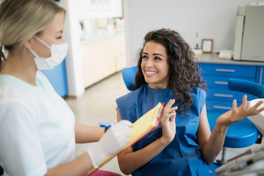 patient sitting in dental chair, talking with hygienist